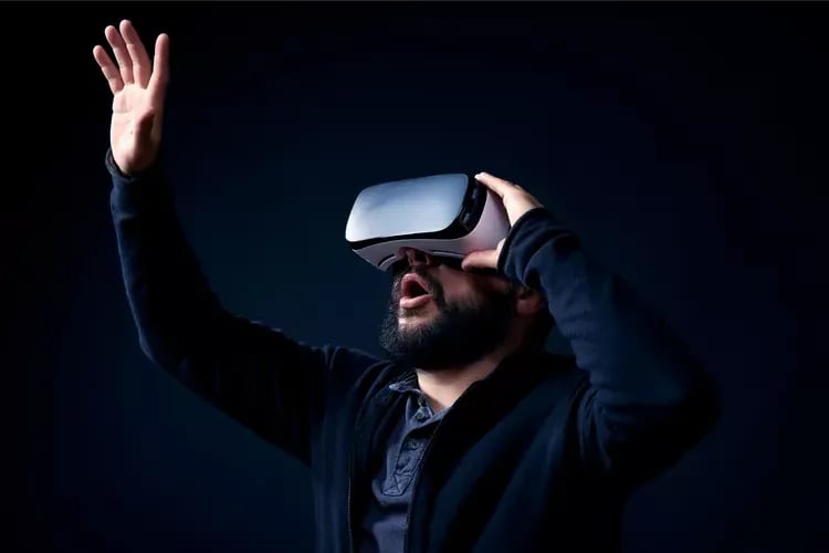 A man wearing a virtual reality headset and reaching into a virtual environment